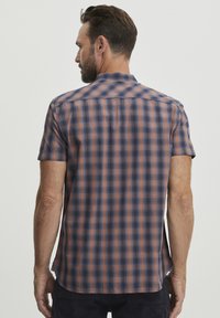 Camisa de botones de manga corta en un patrón de cuadros azul y naranja. Tejido ligero, dobladillo curvado y cuello. Ligera con una sutil textura.