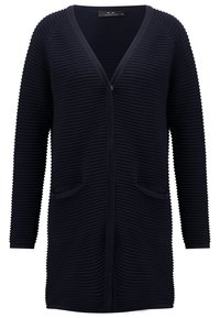 Cardigan bleu marine côtelé à manches longues avec col en V, deux poches avant, et longueur mi-cuisse, fabriqué en tissu texturé.