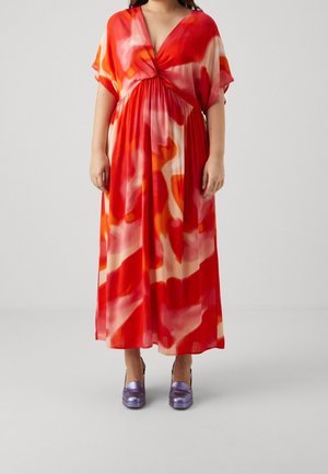 Maxikleid in rotem, orangefarbenem und cremefarbenem abstraktem Muster; leichter Stoff, V-Ausschnitt, kurze Ärmel, geraffte Taille, kombiniert mit violetten High Heels.