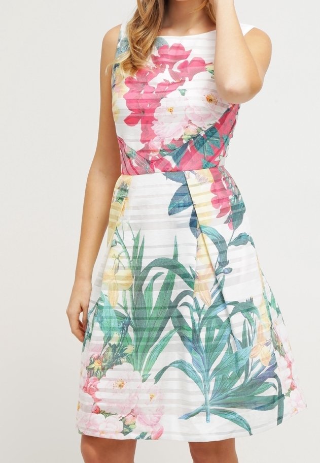 Robe fleurie à design sans manches, jupe plissée, principalement blanche avec des motifs botaniques vifs en rose, jaune et vert.