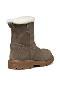 Botín de ante marrón con forro de piel sintética, suela de goma y lengüetas; presenta una etiqueta de impermeabilidad en el tacón.