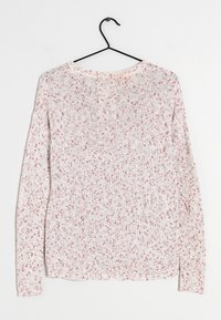 Pull léger à manches longues en tricot blanc et rose avec des nuances. Présente un col rond et des poignets et un ourlet côtelés. Suspendu à un crochet noir.