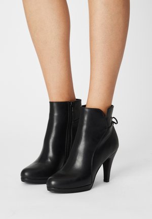 Black leather ankle boots with a mid-height heel. Features a side zipper, rounded toe, and a loop detail at the back. Smooth texture.
