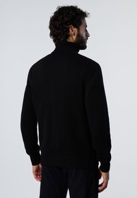 Maglione nero in trama a maglia con collo alto e polsini e orlo a costine. Presenta un motivo testurizzato e una vestibilità comoda, con un colore uniforme in tutta la superficie.
