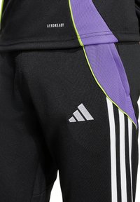 Schwarze Sporthose mit weißen Streifen, lila und grünen Akzenten sowie einem "AEROREADY"-Etikett. Enthält ein Adidas-Logo an der Seite.
