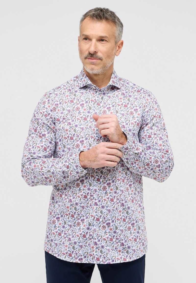 Hvid skjorte med knapper, der har et farverigt blomstermønster med indviklede detaljer. Fremstillet af glat stof med lange ærmer og en klassisk krave.