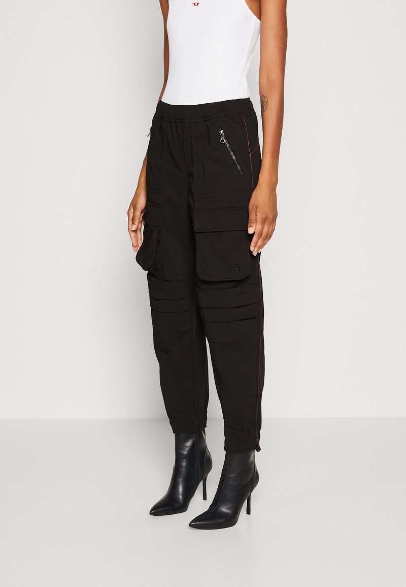 Svarta cargobyxor med elastisk midja, flera fickor och dragsko i öppningen. Bärs med spetsiga svarta ankelstövlar och en vit tanktop.