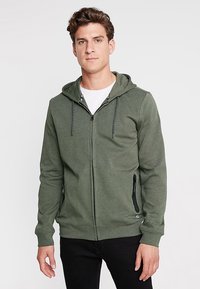 Groene zip-up hoodie met een zachte textuur, verstelbare trekkoordcapuchon, zijzakken met rits en een contrasterend patroon van de binnenvoering.