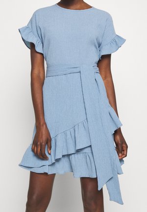 Robe bleu clair avec manches courtes à volants, taille cintrée et ourlet à volants descendant en cascade, réalisée en tissu texturé. Comprend une ceinture à nouer.