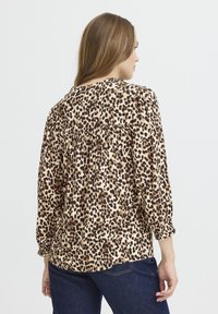 Blúzka s leopardím vzorom z ľahkej látky, s béžovo-čiernym vzorom, so zberaným detailom na zadnej strane a elastickými manžetami.