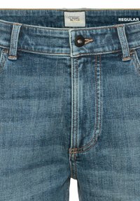 Lichtblauwe denim jeans met een regular fit. Voorzien van een knoopsluiting, oranje stiksels en zijzakken.