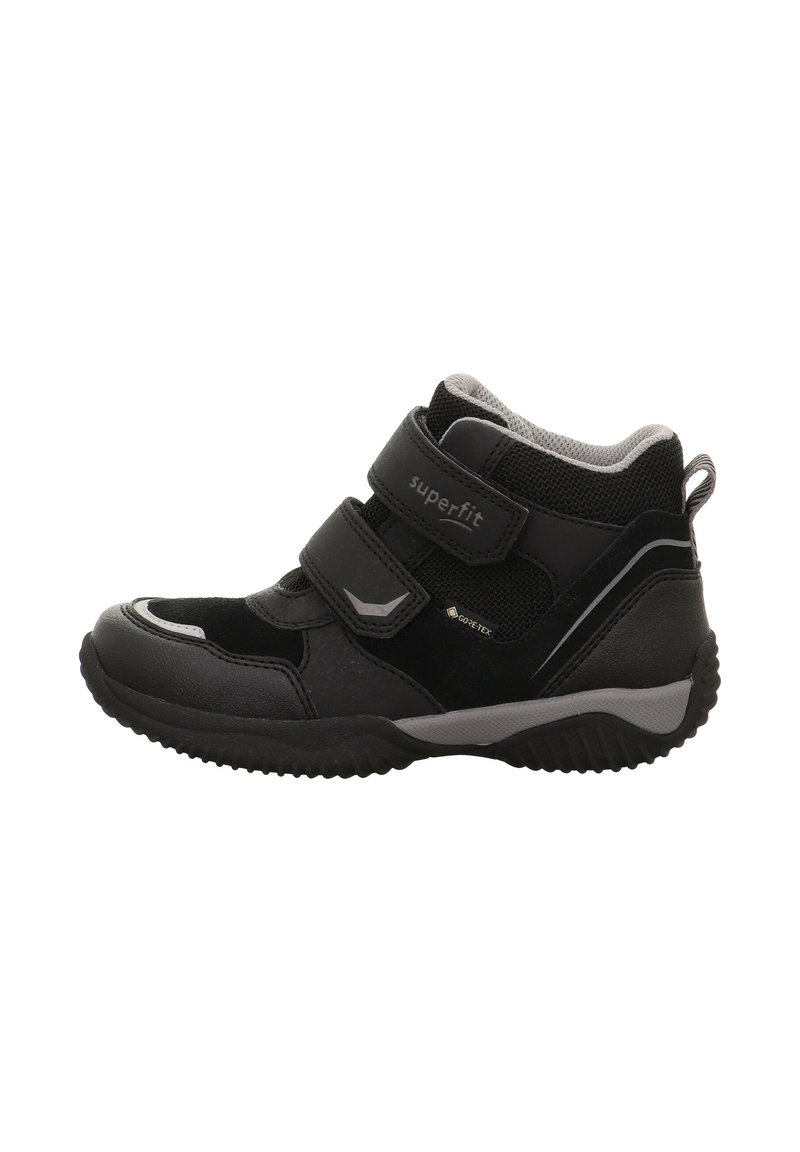 Schwarze Kinderknöchelstiefel aus synthetischem Material, ausgestattet mit zwei Velcro-Riemen, einer strukturierten Oberfläche und einer Gummisohle mit Rillen.