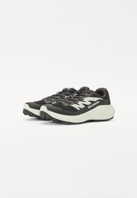 Chaussures de sport noires et grises avec un dessus texturé, logo de la marque blanc et semelle rembourrée, dotées d'une semelle extérieure durable et à motif.