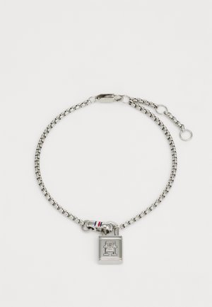 Silver chain bracelet with a padlock charm. Features a small tricolor stripe on the clasp. Links are smooth and metallic in appearance.