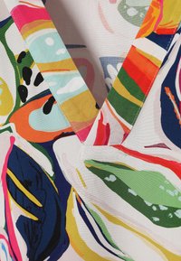 Tissu imprimé floral abstrait coloré avec un col en V cousu dans des tons rouges, verts, bleus, jaunes, roses et blancs.