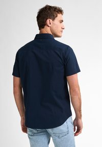 Camicetta a maniche corte di colore blu navy, realizzata in cotone, con colletto button-down e orlo curvo, caratterizzata da un piccolo logo sul retro.