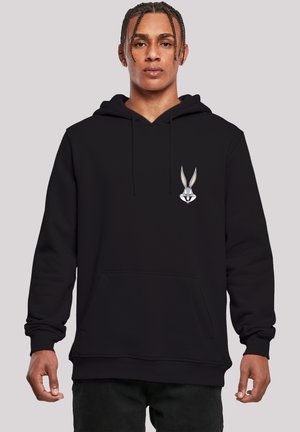 Svart hettegenser med kengurulomme og ribbestrikkede mansjetter, med et Bugs Bunny-trykk på venstre bryst. Materialet ser mykt og behagelig ut.