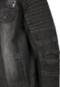 Juodas džinsinis švarkas su tekstūriniais raibais pečių akcentais, nusidėvėtais elementais, su sagomis uždaroma krūtinės kišene ir šoninėmis kišenėmis.