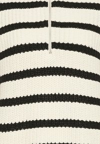 Pletený pulóver s štvrtinovým zipsom, so striedavými hrubými čierno-bielymi horizontálnymi pruhmi. Textúra vyzerá trochu hrubo.