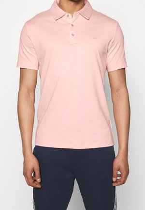 Jasnoróżowa koszulka polo z klasycznym kołnierzem, krótkimi rękawami, rozcięciem na trzy guziki i małym logo na piersi. Gładka faktura.