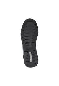 Suela de zapato de goma negra con un patrón de relieve profundo. Presenta secciones acanaladas para mayor agarre y un detalle de logotipo plateado. Forma plana y redondeada.