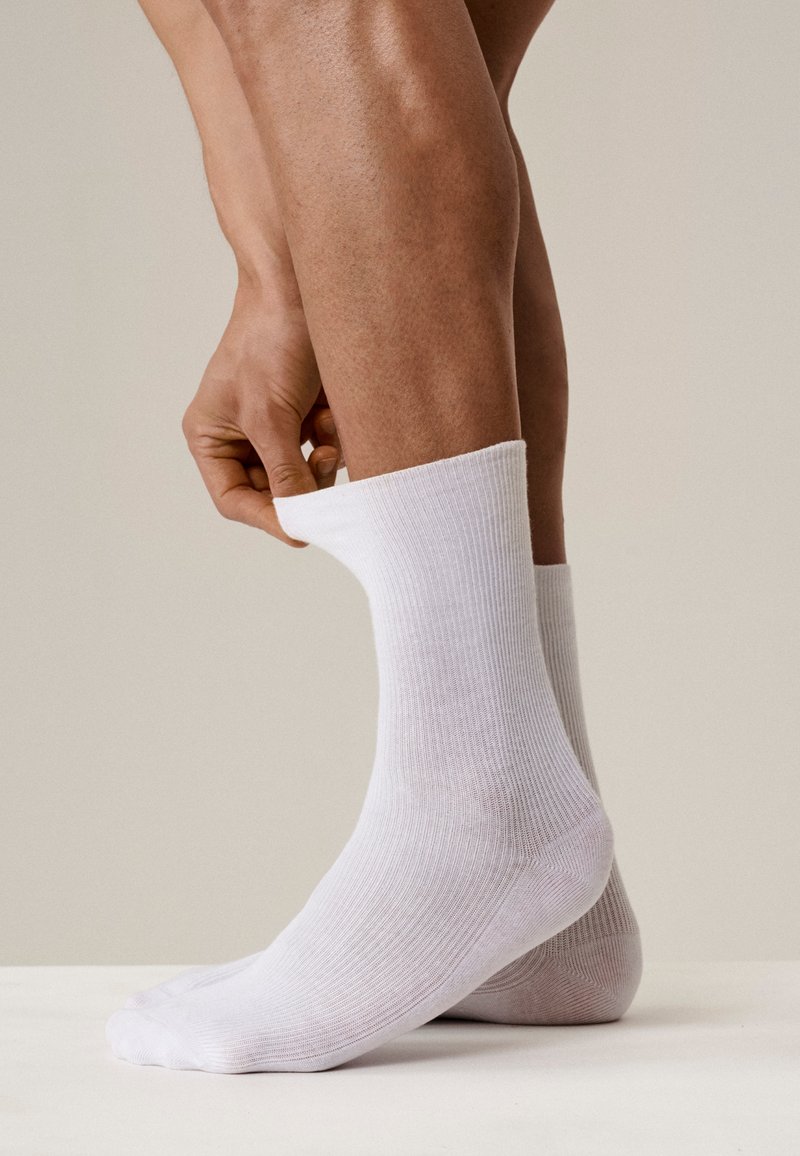 Białe skarpetki prążkowane, zakładane na kostkę, prezentujące gładki, lekki materiał i standardowy krój do kostek.