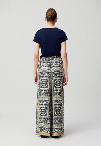 Camiseta de manga corta en color azul marino combinada con pantalones de pierna ancha que presentan un intrincado patrón geométrico en azul y crema, con cintura fruncida y bolsillos.