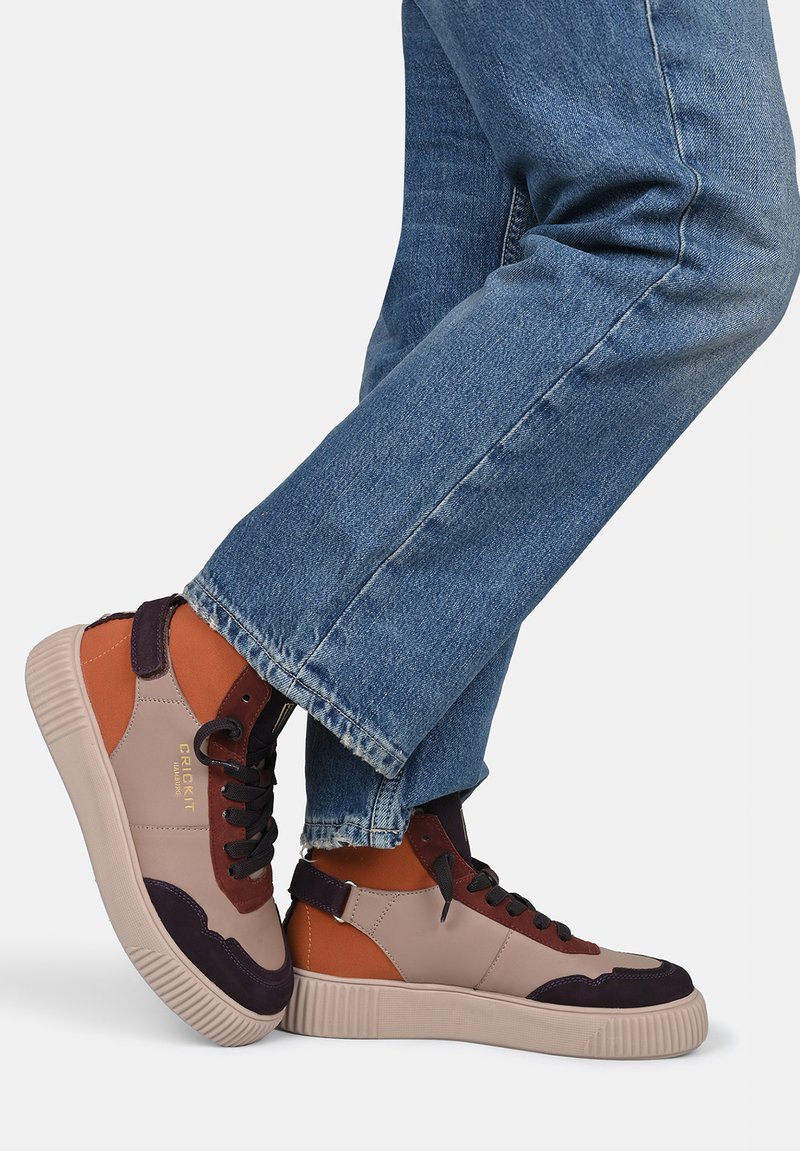 High-top sneakers featuring a mix of beige, brown, and dark purple materials, with a textured rubber sole and black laces.