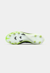 Black and white soccer cleat sole with green accents, featuring multiple studs and a textured surface for traction, branded with "Copa."