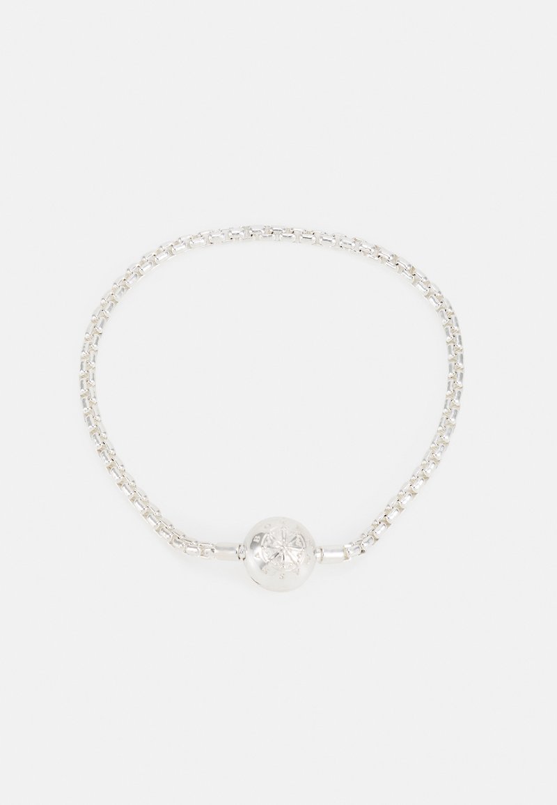 Bracelet chaîne en argent avec un fermoir rond orné d'un motif d'étoile gravé, présenté sur un fond blanc.