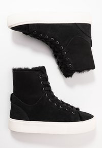 Czarne zamszowe sneakersy w wysokim kroju z czarnymi sznurówkami, białymi grubymi gumowymi podeszwami i widocznym czarnym futrem w środku.