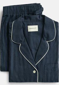 Marineblauw gestreept katoenen pyjamaset met witte bies, bestaande uit een overhemd met kraag en een broek met elastische tailleband. Merklabel zichtbaar.