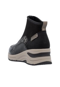 Botte de cheville noire en tissu texturé et cuir lisse. Elle présente un accent à motifs, une semelle chunky de couleur claire et une fermeture éclair sur le côté.