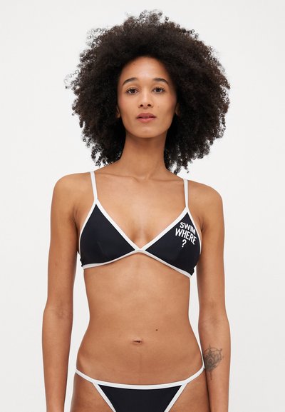 Set di bikini nero con top triangolare bordato di bianco e testo stampato "SWIM WHERE?". Tessuto morbido e liscio con design minimalista.
