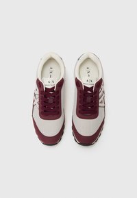 Baskets de sport bordeaux et gris en matériau mesh et suède, avec un bout rond, un laçage à l'avant et une semelle en caoutchouc texturée.