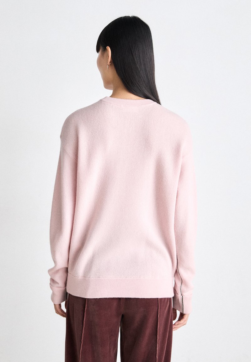 Helles rosa, gestricktes Sweatshirt mit lockerer Passform, gerippten Bündchen und Saum. Weiche Textur, runder Ausschnitt und minimalistisches Design.