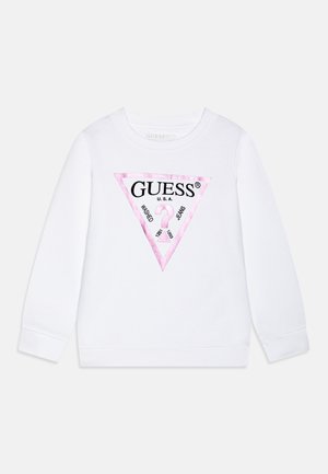 Sweat-shirt blanc à manches longues avec un logo triangulaire rose sur la poitrine portant l'inscription « GUESS U.S.A. Washed Jeans » et un point d'interrogation à l'intérieur.