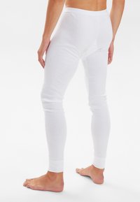 White cotton leggings with a close fit. Features a soft waistband, streamlined design, and ribbed cuffs. Exposed skin on feet and back.