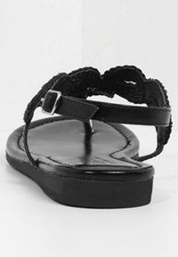 Sorte læder flade sandaler med vævede remme og en justerbar spænde. Glat tekstur med et minimalistisk design og flad sål.
