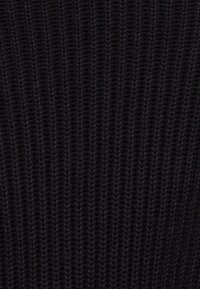 Primo piano di tessuto a maglia a coste nero scuro con motivo di cuciture verticali strutturate.