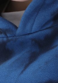 Sudadera azul con tejido texturizado, con un prominente escote en forma de V y un diseño suave y casual, destacado por un sombreado sutil.