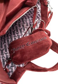 Czerwona zamszowa torba na ramię z zamkiem błyskawicznym, w zestawie z mniejszą, dopasowaną saszetką oraz wzorzystą podszewką z logo "Juicy Couture."
