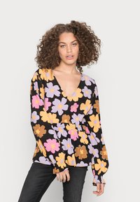 Blusa preta com padrão floral e mangas longas, apresentando padrões de flores roxas, cor-de-rosa e amarelas, com um decote em V profundo e ajustada na cintura.
