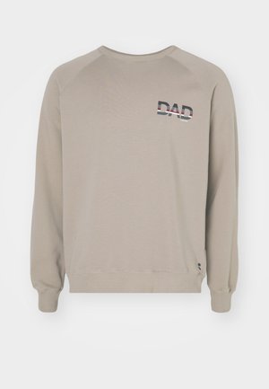 Beige collegepaita, jossa pitkät hihat, resoroitu pyöreä kaulus ja monivärisellä tekstillä painettu "DAD" vasemmassa yläkulmassa. Pehmeä rakenne.