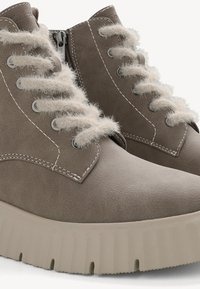 Graue Kunstleder-Ankle Boots mit flauschigen beigen Schnürsenkeln, gepolstertem Kragen und dicker weißer Plateausohle. Flache Schnürsenkel und subtile Nähdetails.