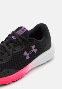 Černá sportovní bota s texturovaným svrškem, fialovými akcenty na jazyku a logu a gradientní podrážkou přecházející z růžové do bílé.