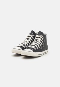 Zapatillas altas de lona azul marino oscuro con suelas de goma blanca, que presentan cordones blancos, ojales de metal y una puntera texturizada.