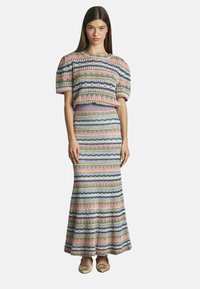 Gebreid tweedelig jurkje met korte pofmouwen en een lange rok. Kenmerkt zich door meerkleurige strepen in roze, blauw, groen en crème.