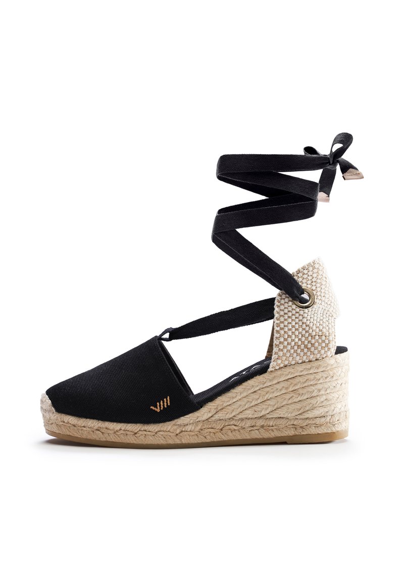 Espadrille wedge in tela nera con suola in juta intrecciata, dotata di cinturini neri incrociati e accentuazione del tallone in beige texturizzato.