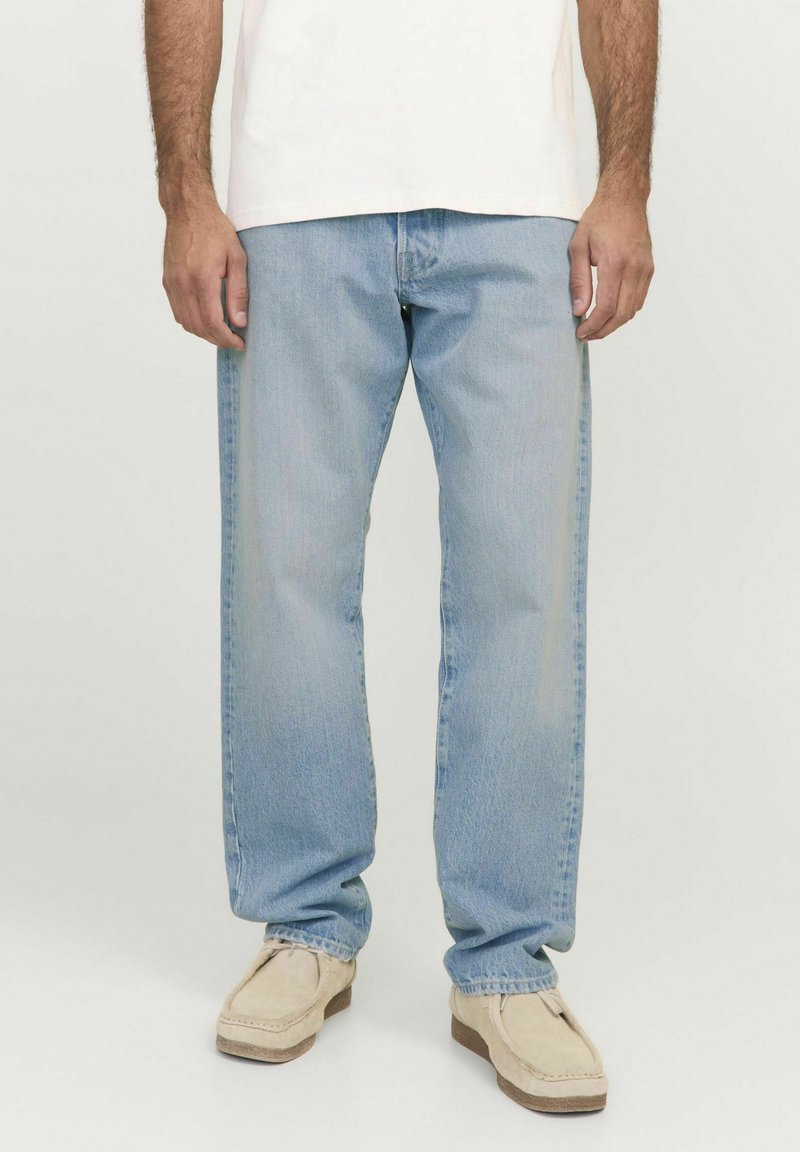 Jeans in denim azzurro chiaro con taglio dritto, caratterizzati da una finitura sbiadita e design a cinque tasche, indossati con scarpe slip-on beige.